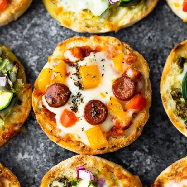 overhead shot of a variety of english muffin pizzas on gray background