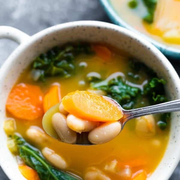 overhead shot of a white bowl and spoon filled with smoky white bean and kale soup