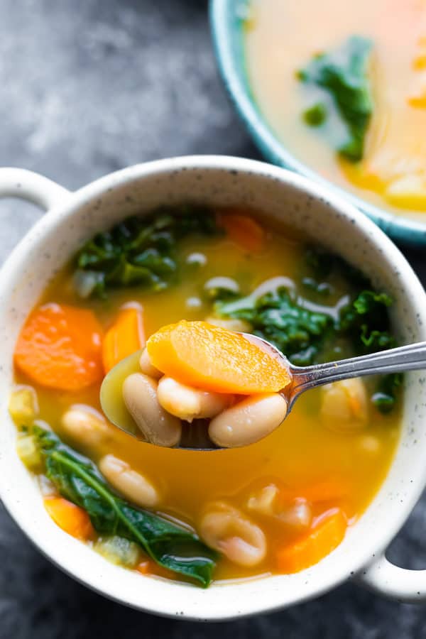 overhead shot of a white bowl and spoon filled with smoky white bean and kale soup