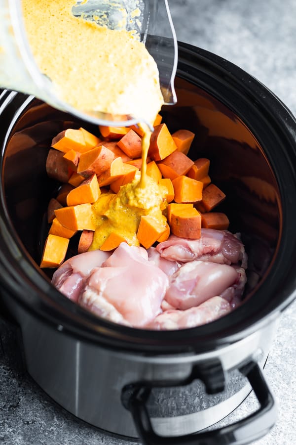 pouring the sauce for dairy-free chicken korma into the slow cooker