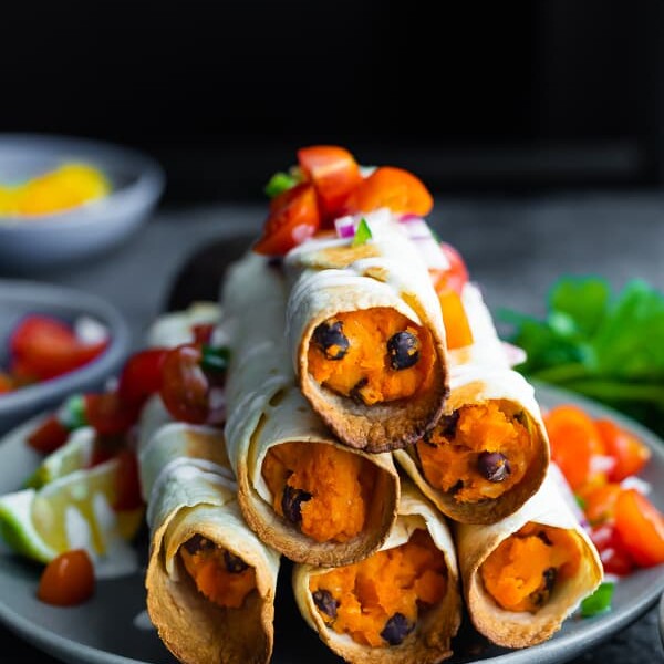 a stack of six black bean baked taquitos on a gray plate