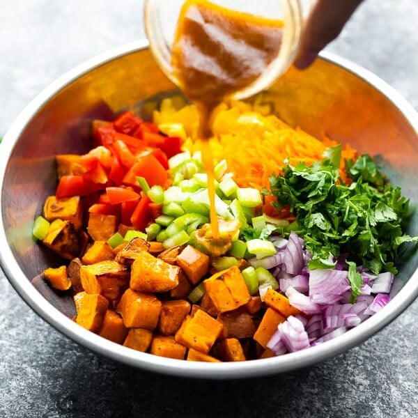 hand pouring jar of dressing onto the southwestern wild rice and sweet potato salad