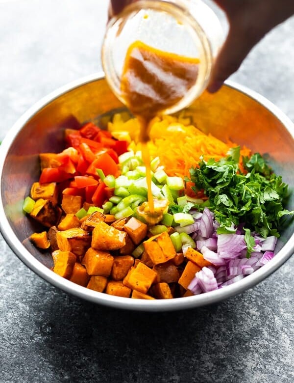 hand pouring jar of dressing onto the southwestern wild rice and sweet potato salad