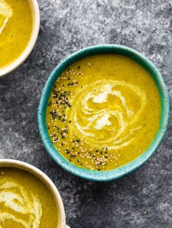 overhead shot of a blue bowl filled with broccoli turmeric soup with sesame seeds on top