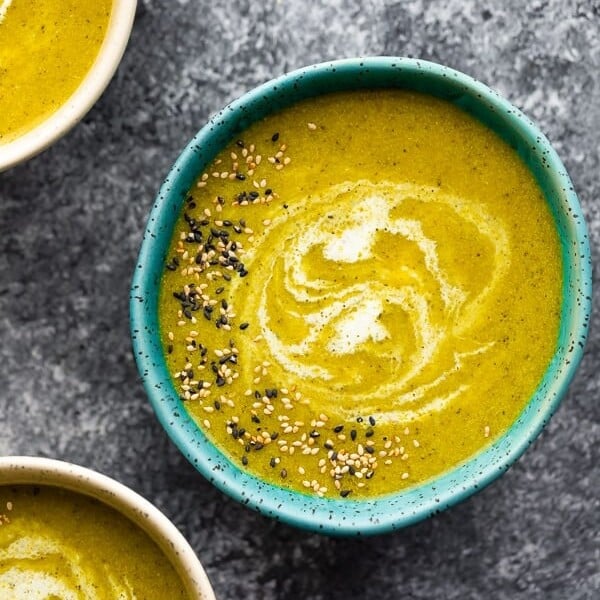 overhead shot of a blue bowl filled with broccoli turmeric soup with sesame seeds on top