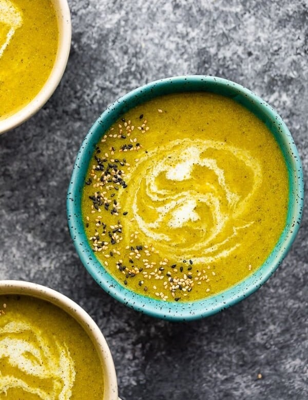 overhead shot of a blue bowl filled with broccoli turmeric soup with sesame seeds on top