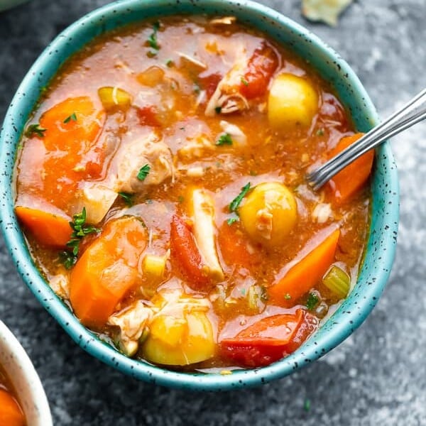 overhead shot of tuscan chicken stew in a blue bowl with a spoon