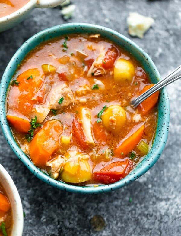 overhead shot of tuscan chicken stew in a blue bowl with a spoon