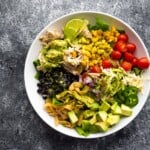 overhead shot of beer chicken taco salad with cilantro vinaigrette in a white bowl on gray background
