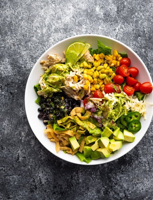 overhead shot of beer chicken taco salad with cilantro vinaigrette in a white bowl on gray background