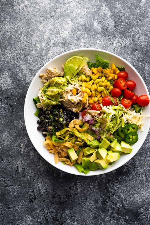 overhead shot of beer chicken taco salad with cilantro vinaigrette in a white bowl on gray background