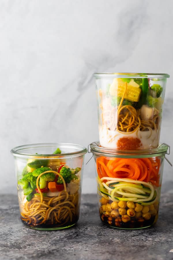 Stack of three jars filled with healthy instant noodles and fresh veggies