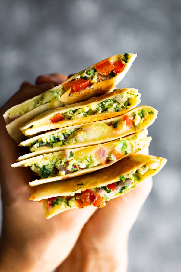 Hand holding five spinach feta breakfast quesadillas