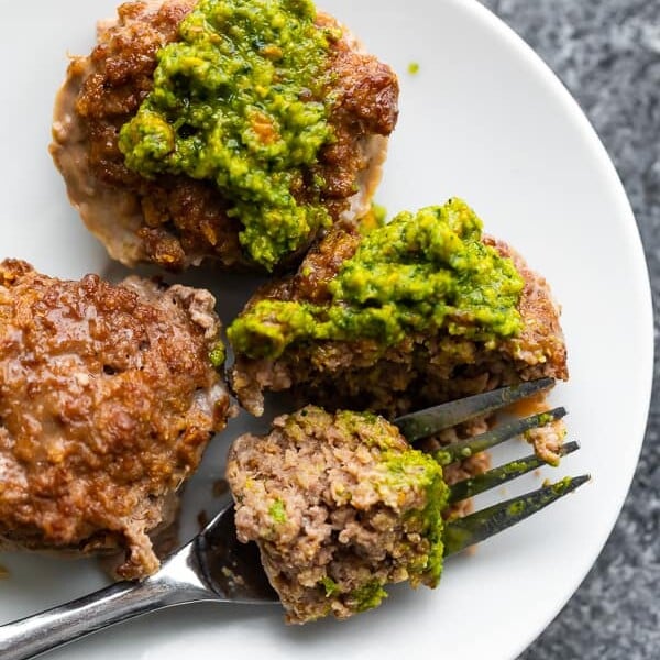 Overhead shot of multiple moroccan mini meatloaf cups on white plate with a fork