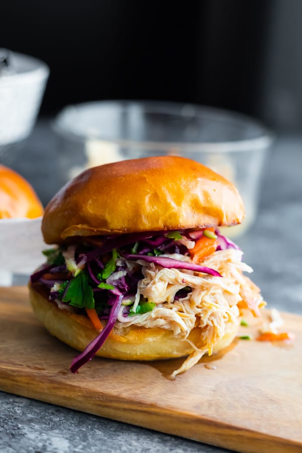 A close up of honey lime shredded chicken sandwich on a wood cutting board