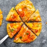 Overhead shot of thai chicken naan pizza cut into wedges on gray background