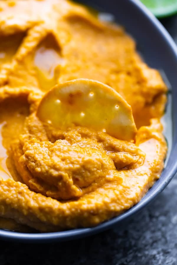 cracker dipping in the Smoky Sweet Potato Hummus