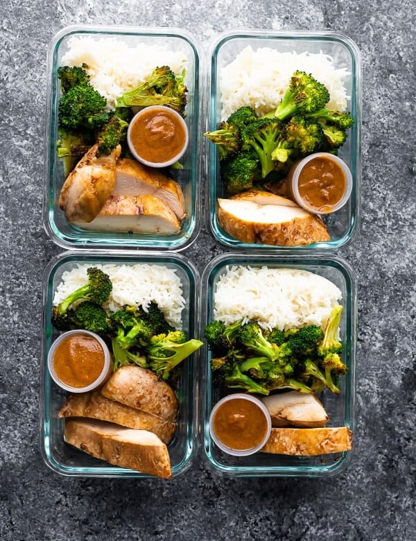 overhead shot of four glass meal prep containers filled with thai chicken lunch bowls