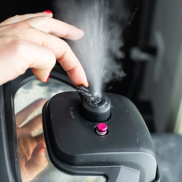 Picture of a hand releasing the pressure on an instant pot