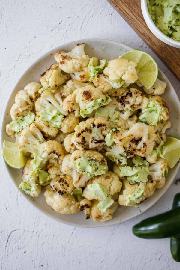 bowl of grilled cauliflower with jalapeno lime butter dolloped all over