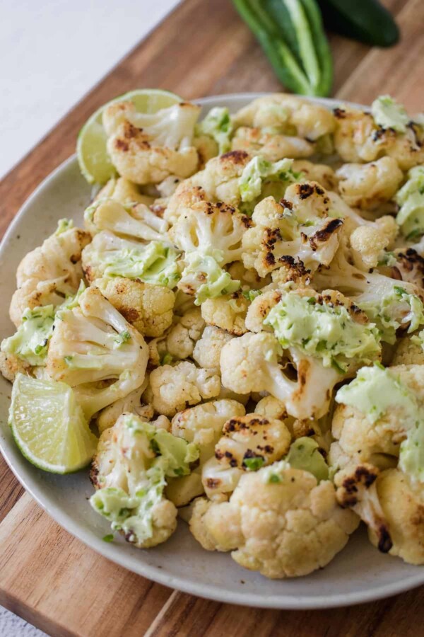 bowl of grilled cauliflower with jalapeno lime butter dolloped all over