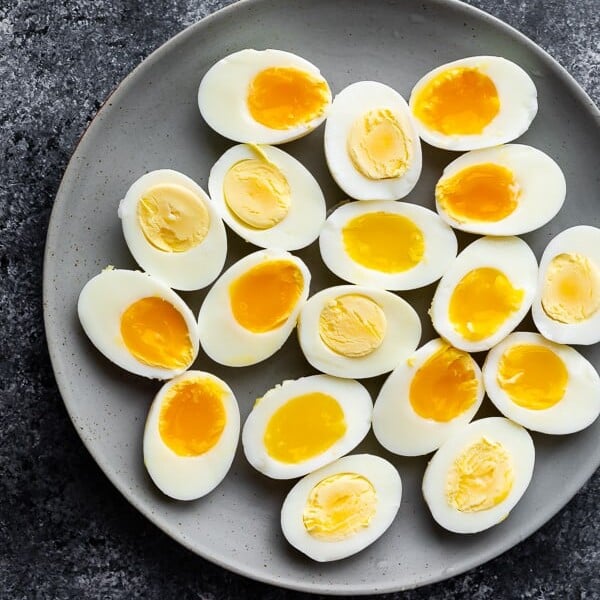 Lots of halved hard and soft boiled eggs laying on a gray plate