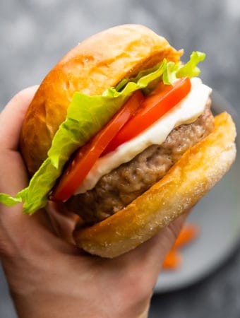 hand holding up a perfect juicy turkey burger with lettuce and tomato slices