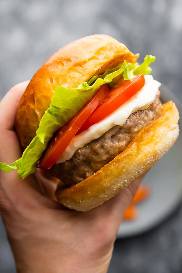 hand holding up a perfect juicy turkey burger with lettuce and tomato slices