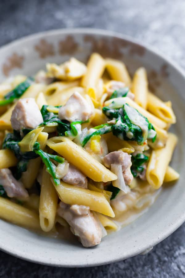 Spinach and artichoke pasta in a white bowl