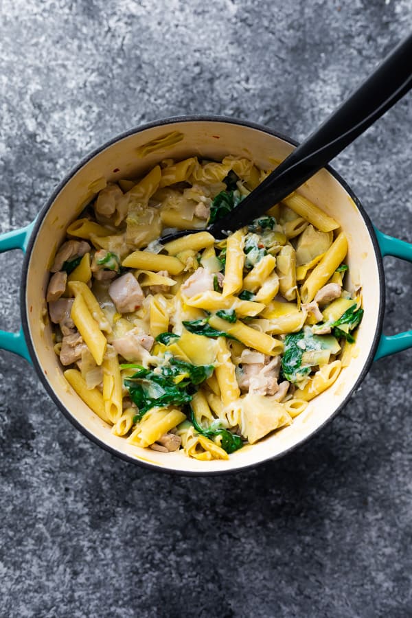 spinach artichoke pasta in pot with serving spoon