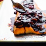 Salmon with a spoon drizzling strawberry balsamic reduction on top