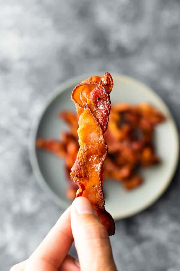 hand holding a strip of air fryer bacon