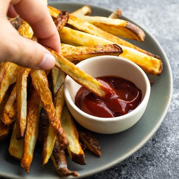 dipping an air fryer french fry into ketchup