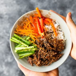 hands holding honey garlic beef rice bowl