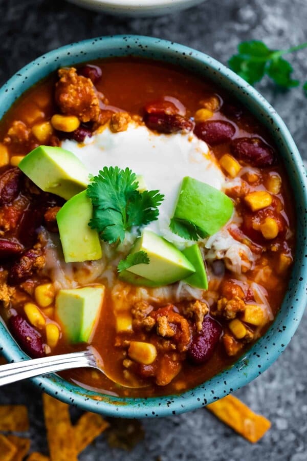 instant pot turkey chili in a bowl with toppings and spoon