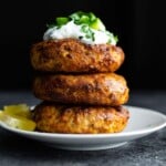 stack of air fryer salmon patties topped with yogurt and cucumbers
