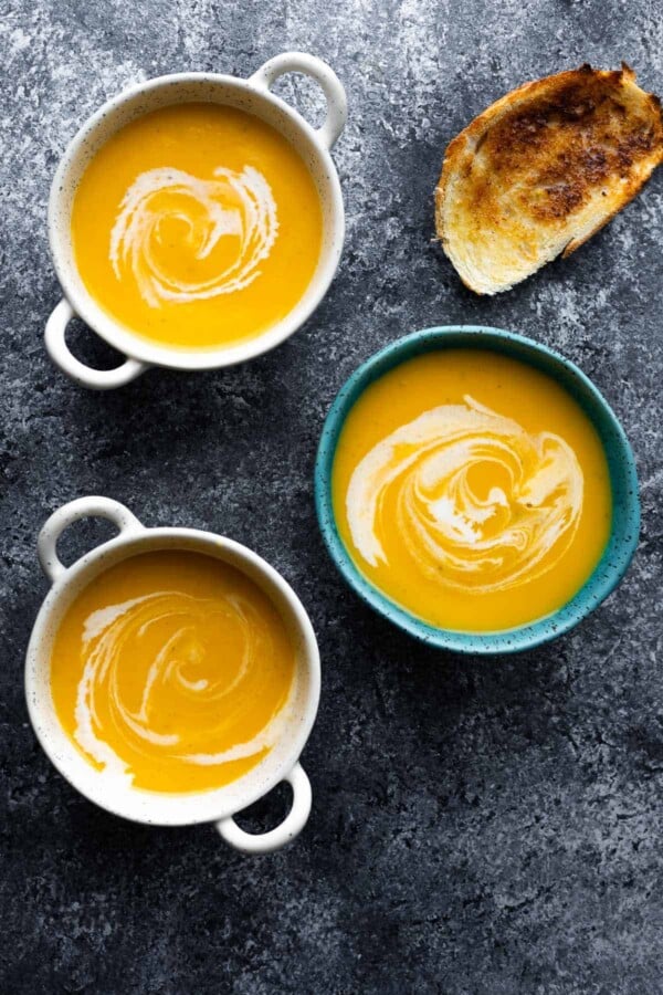 three bowls of instant pot butternut squash soup with toasted bread beside them