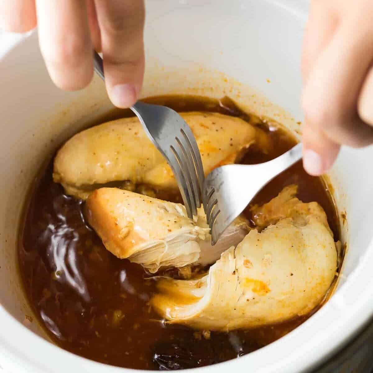 chicken in chipotle honey sauce in white bowl being shredded