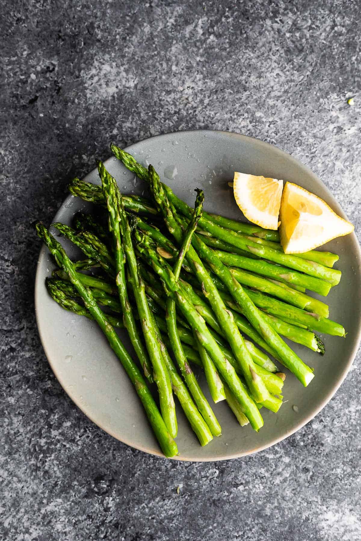 air fryer asparagus on plate with lemon wedges
