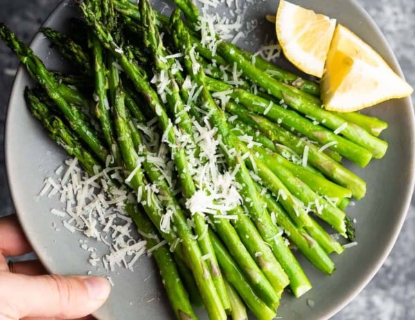 holding plate of asparagus with parmesan cheese