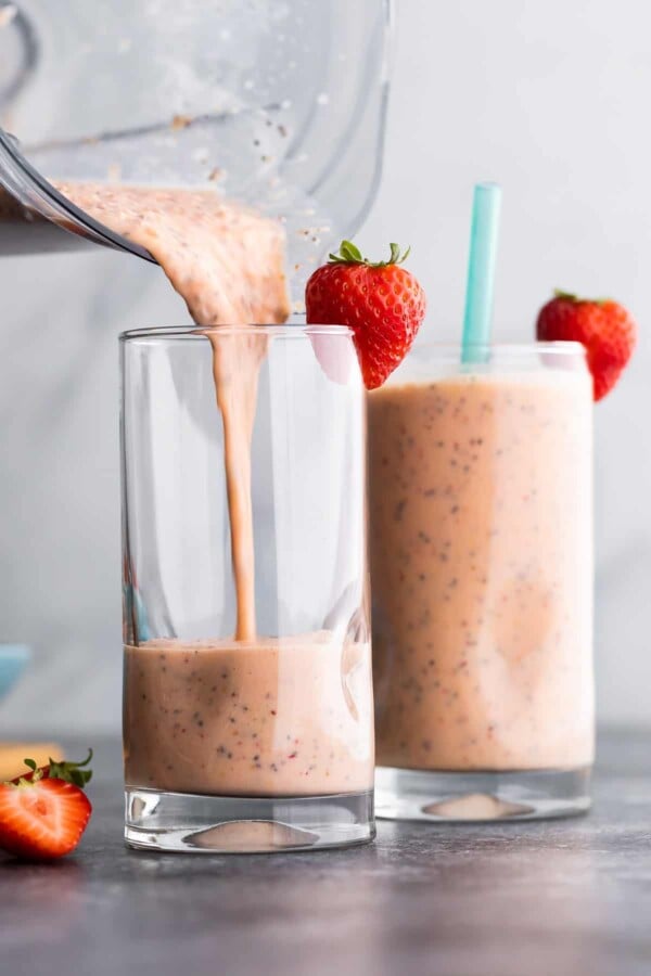 pouring strawberry smoothie out of blender into glass