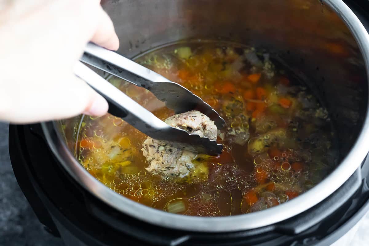 pulling chicken out of the instant pot to shred it
