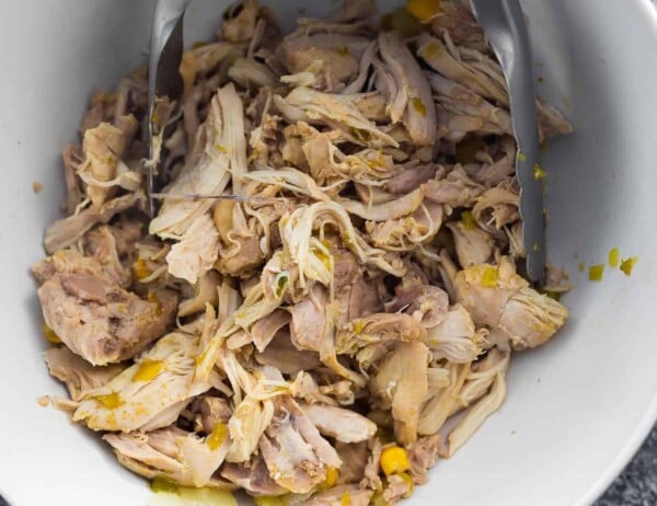 shredded chicken in a bowl with tongs
