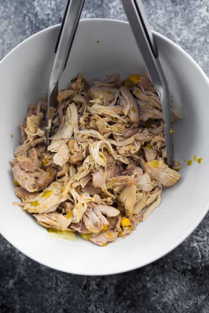 shredded chicken in a bowl with tongs