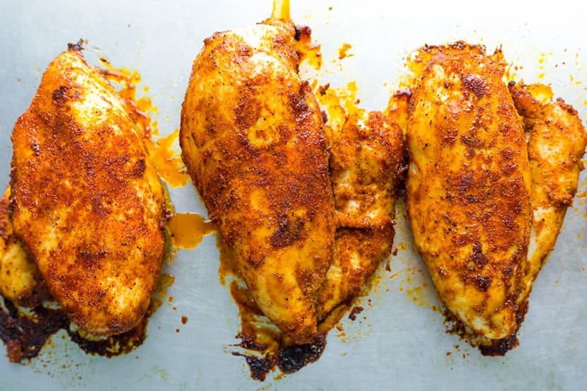 three baked chicken breasts on a sheet pan