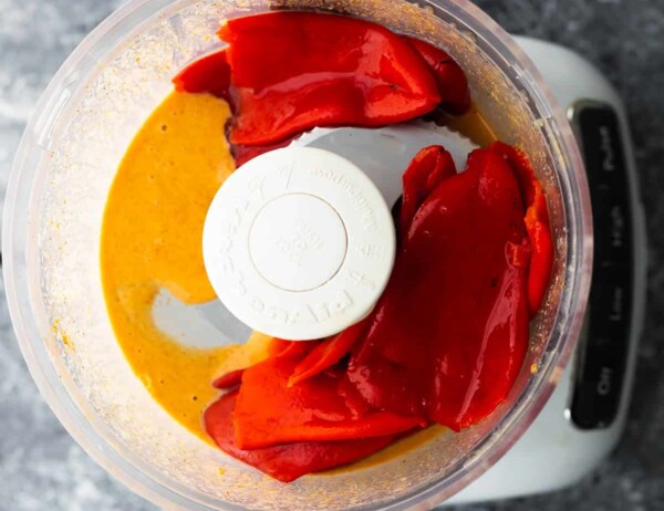 adding roasted red peppers to liquid in food processor for roasted red pepper hummus