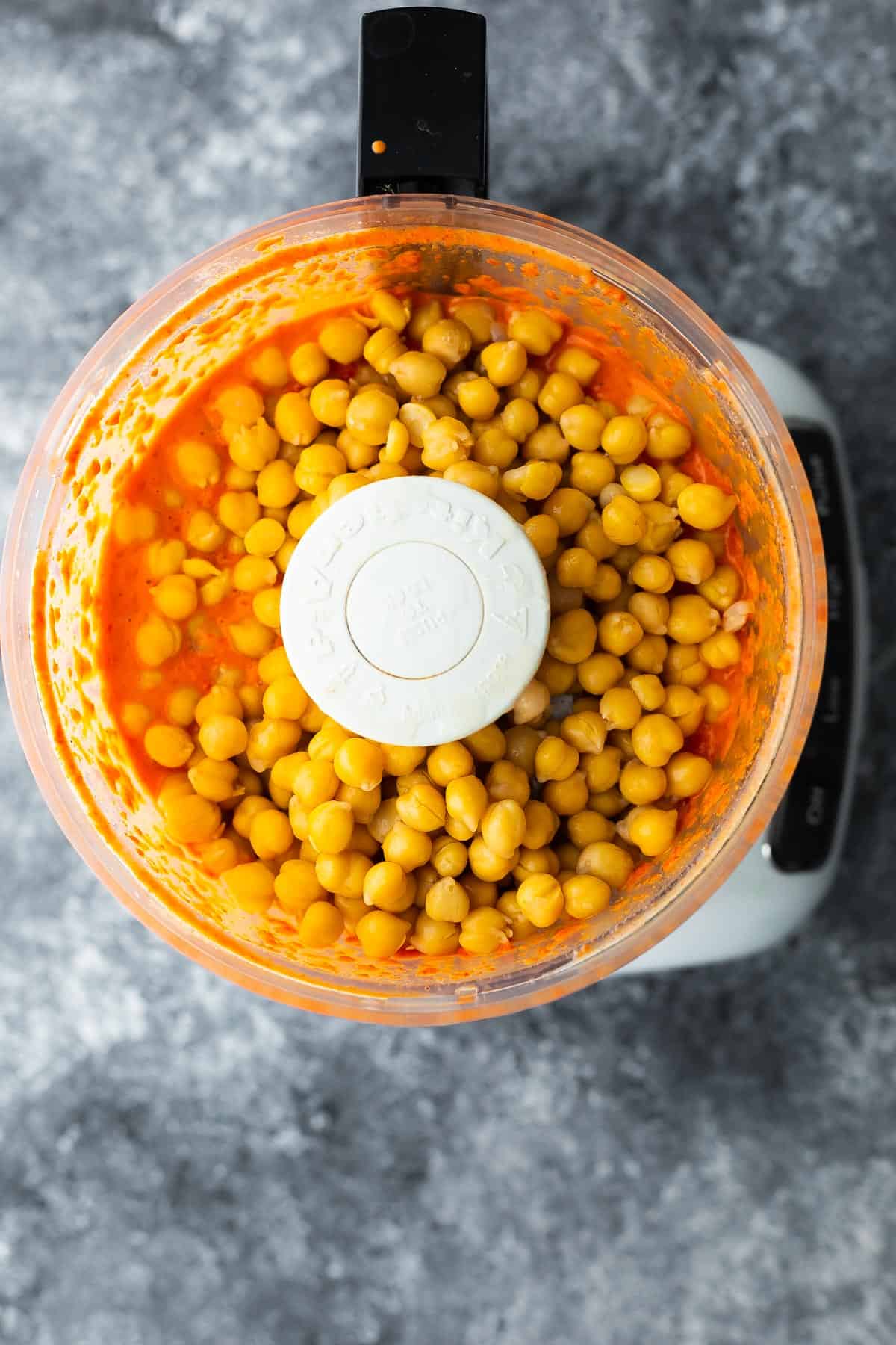 chickpeas added to liquid in food processor to make roasted red pepper hummus