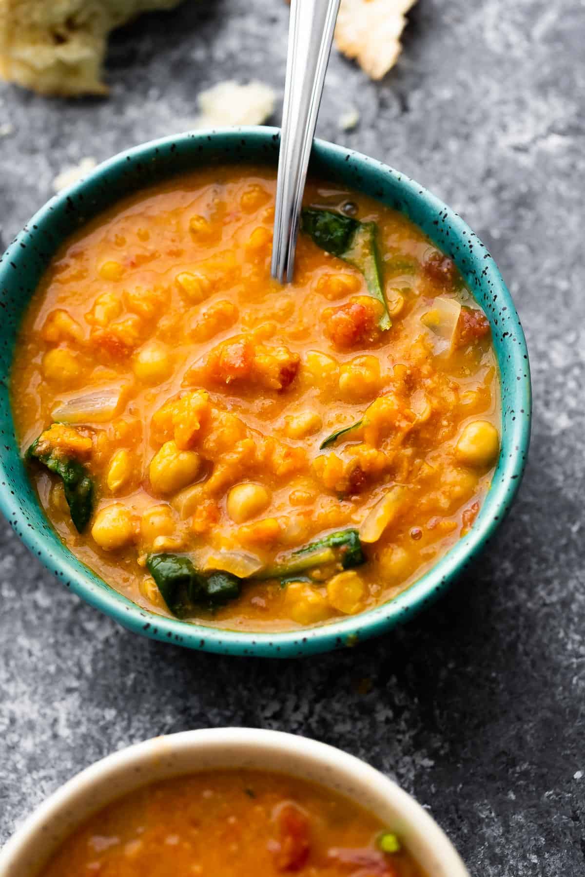 peanut stew in bowl with spoon, bread in background