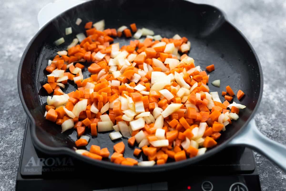 carrots and onions sauteeing in a skillet