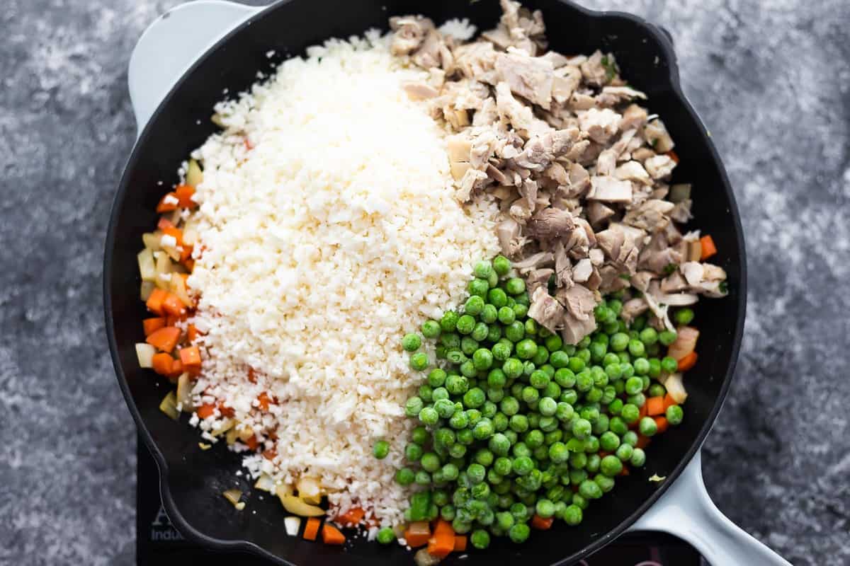 riced cauliflower, frozen peas and cooked chicken added to a skillet